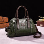 Sac à main en cuir vert foncé avec poignées marron, design élégant, étiquette métallique, posé sur une table blanche, fond noir. Accessoire mode tendance.