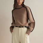 Femme portant un pull col roulé marron avec bordures noires, ceinture noire et pantalon beige. Mode automne-hiver élégante et moderne.