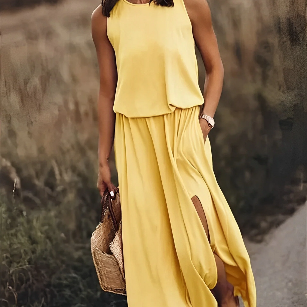Femme en robe longue jaune, tenant un sac en osier, marchant dans un champ. Mode estivale, élégance décontractée, style bohème chic.