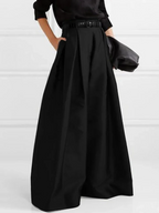 Femme portant une jupe longue noire élégante avec ceinture, chemise noire et pochette. Mode chic, tenue sophistiquée, style minimaliste.