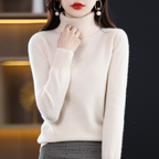 Femme portant un pull col roulé blanc, élégant et moderne, avec des boucles d'oreilles perle, mode automne-hiver, style chic et tendance.