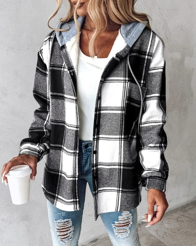 Femme portant une chemise à carreaux noir et blanc, tenue décontractée avec jean déchiré, tenant un gobelet de café. Mode automne tendance.