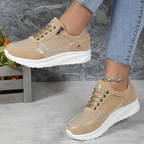 Chaussures de sport beiges pour femme avec semelle blanche, portées avec un jean. Design moderne et confortable, idéal pour la mode urbaine.