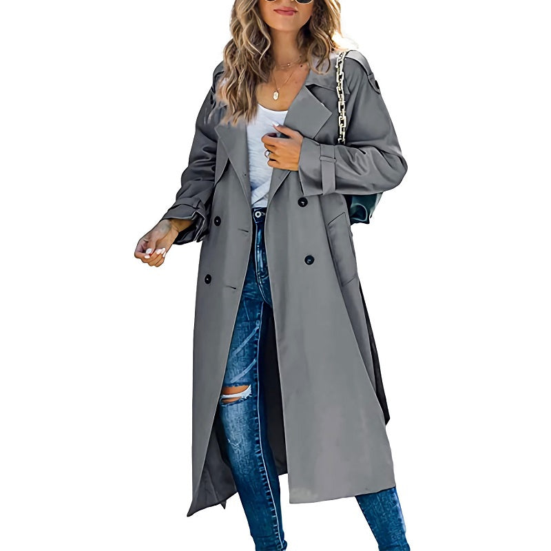 Femme portant un trench-coat gris élégant, jeans déchirés et sac à main chaîne. Mode automne, style urbain chic, tendance vestimentaire.