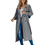 Femme portant un trench-coat gris élégant, jeans déchirés et sac à main chaîne. Mode automne, style urbain chic, tendance vestimentaire.