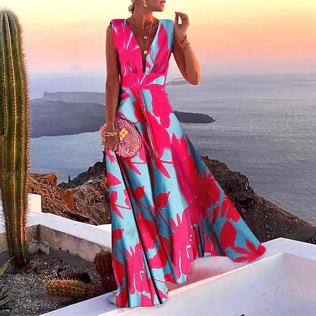 Robe longue fleurie rose et bleue, femme élégante, coucher de soleil en bord de mer, cactus, paysage méditerranéen, mode estivale chic.