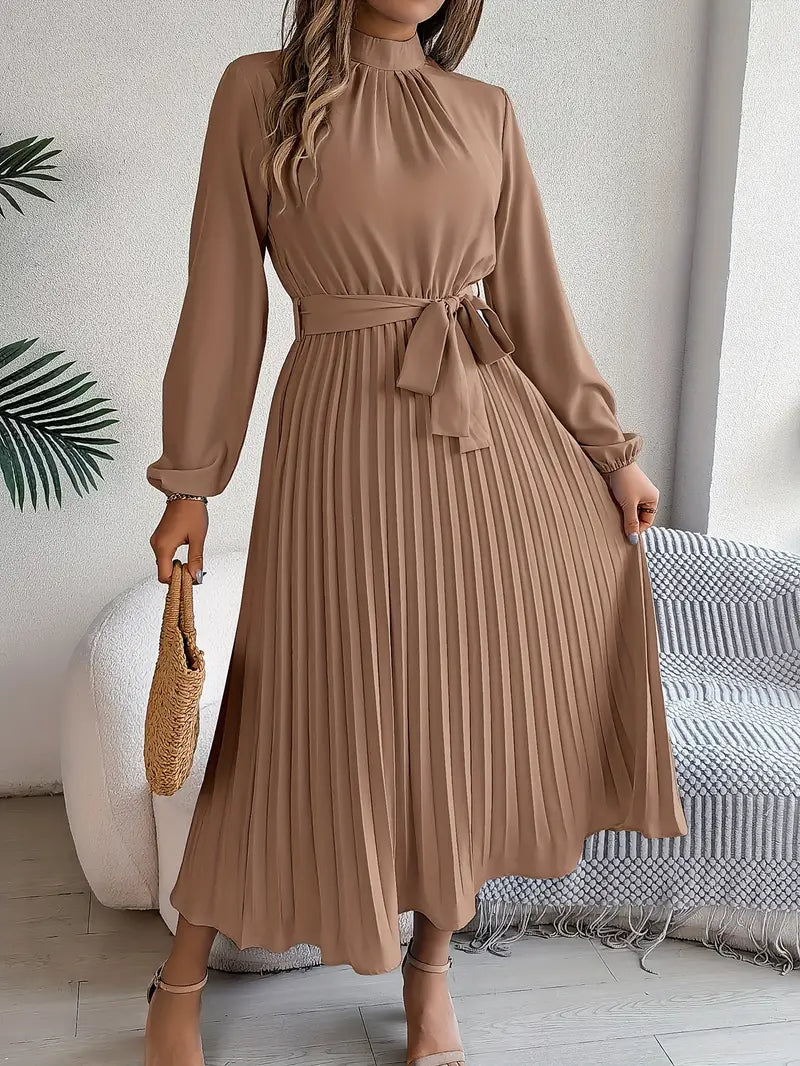 Robe longue plissée marron avec manches longues, ceinture nouée à la taille, tenue élégante pour femme, accessoirisée d'un sac en osier.