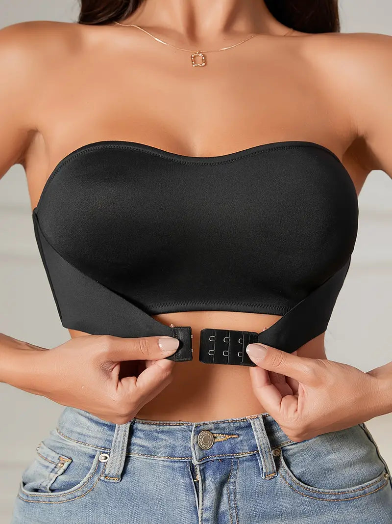 Femme portant un bustier noir sans bretelles, ajustant la fermeture avant. Mode féminine, top élégant, style moderne, jeans décontracté.