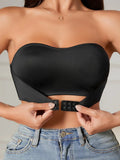 Femme portant un bustier noir sans bretelles, ajustant la fermeture avant. Mode féminine, top élégant, style moderne, jeans décontracté.