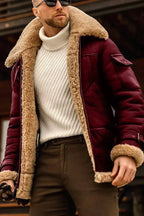 Homme portant un manteau aviateur en cuir bordeaux avec doublure en fourrure beige, pull col roulé blanc, lunettes de soleil, mode hiver élégante.