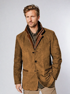 Homme portant une veste en cuir marron, col relevé, sur chemise kaki. Mode masculine élégante, style automne-hiver, tendance vestimentaire.