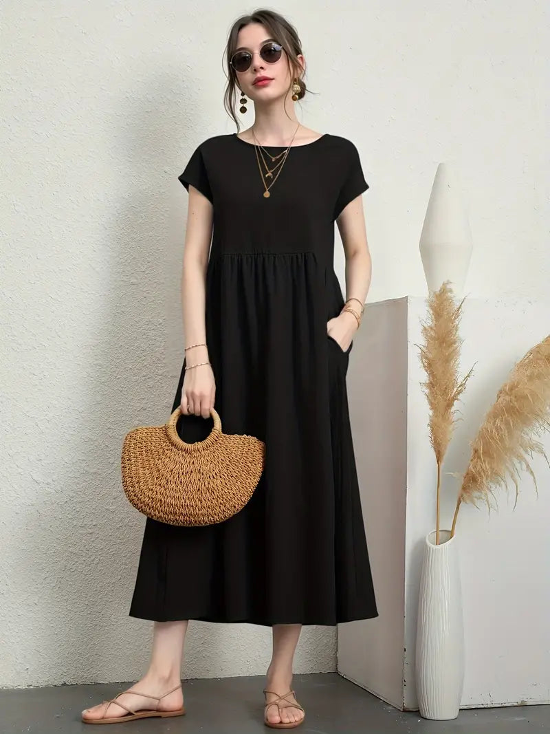 Femme en robe noire élégante, portant un sac en osier, debout près d'un vase avec des pampas. Mode chic, accessoires tendance, style décontracté.