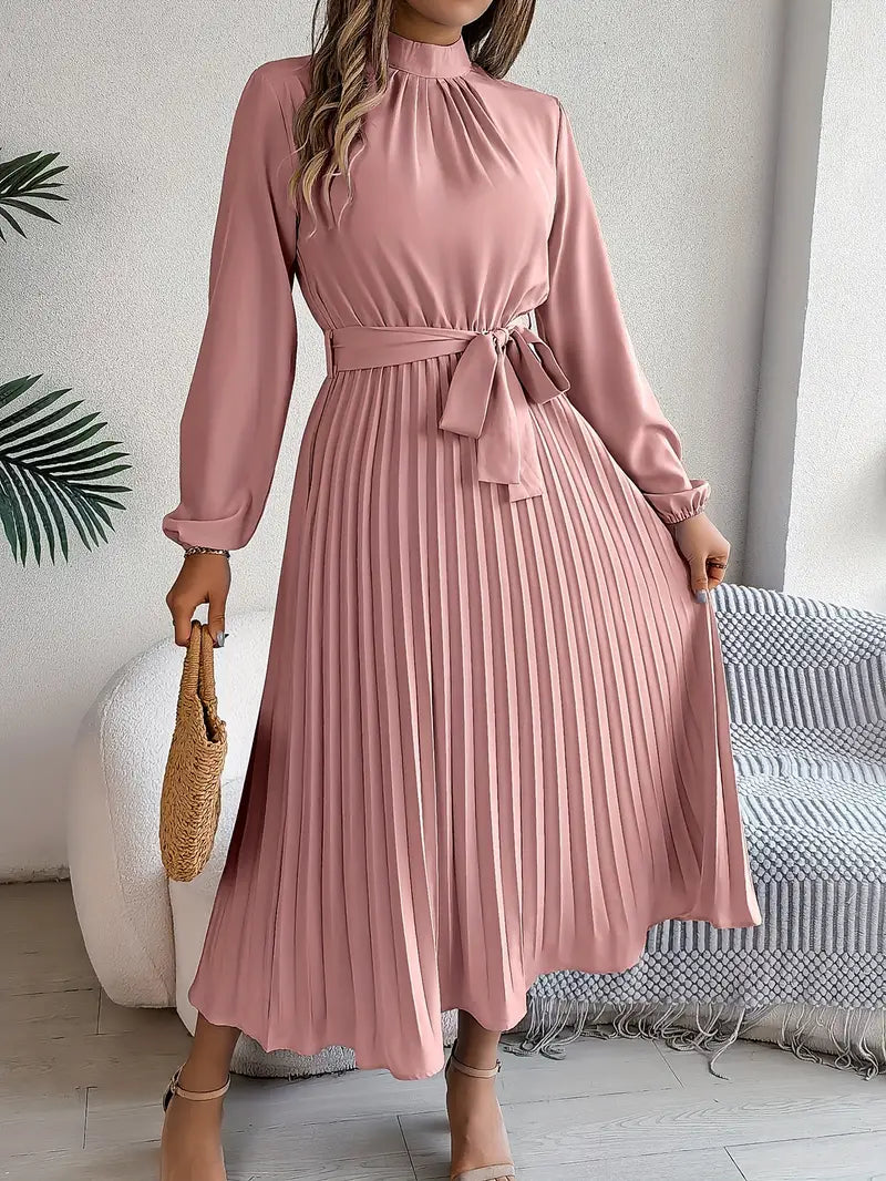 Robe rose plissée élégante avec manches longues, ceinture nouée à la taille, tenue chic pour femme, mode tendance, fond intérieur moderne.