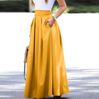 Femme en jupe longue jaune élégante, portant un haut blanc, montre argentée, sac à main marron. Mode féminine chic, tenue estivale tendance.