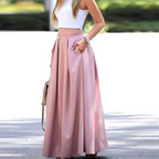 Femme en jupe longue rose élégante, top blanc sans manches, posant à l'extérieur. Mode féminine chic, tenue estivale tendance, style décontracté.
