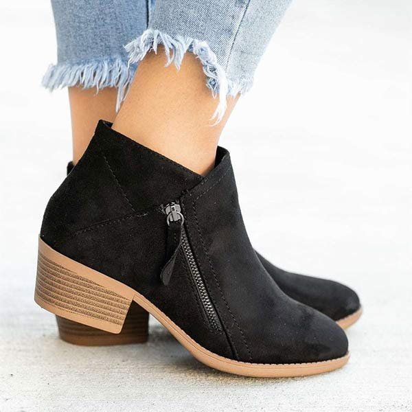 Bottines noires en daim avec talon carré, fermeture éclair latérale, portées avec un jean effiloché. Chaussures tendance automne-hiver pour femmes.