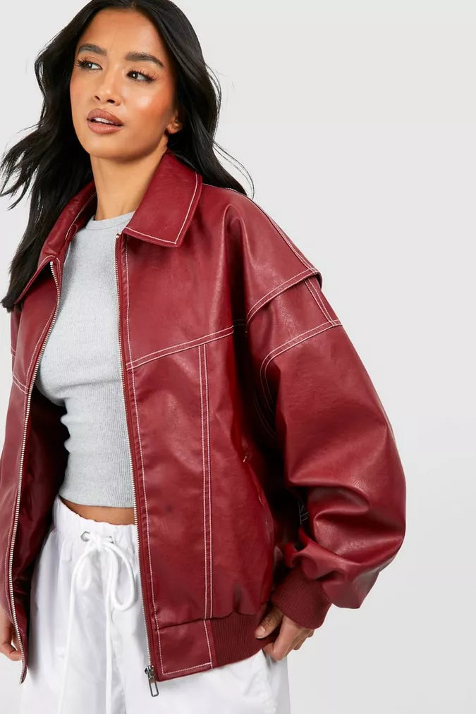 Femme portant une veste en cuir rouge sur un t-shirt gris et un pantalon blanc. Mode automne, style décontracté, tendance vestimentaire.
