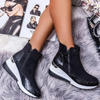 Bottes noires en cuir texturé sur tapis en fourrure grise, avec magazines de mode en arrière-plan. Chaussures tendance, style moderne et élégant.