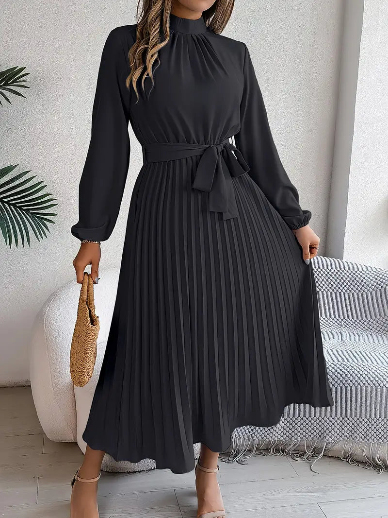 Robe longue noire plissée élégante avec manches longues, ceinture nouée à la taille, portée par une femme tenant un sac en osier.