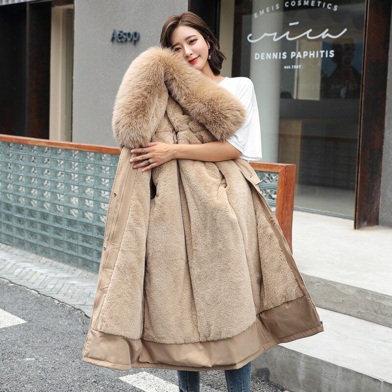 Femme portant un manteau en fausse fourrure beige, devant une boutique moderne. Mode hiver élégante, tendance, confort et style urbain.