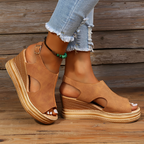 Sandales compensées marron en cuir texturé, portées avec un jean déchiré. Chaussures d'été tendance, mode féminine, style décontracté chic.
