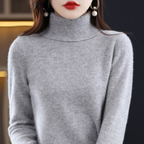Femme portant un pull col roulé gris, boucles d'oreilles pendantes, lèvres rouges. Mode hiver élégante, style chic et moderne.