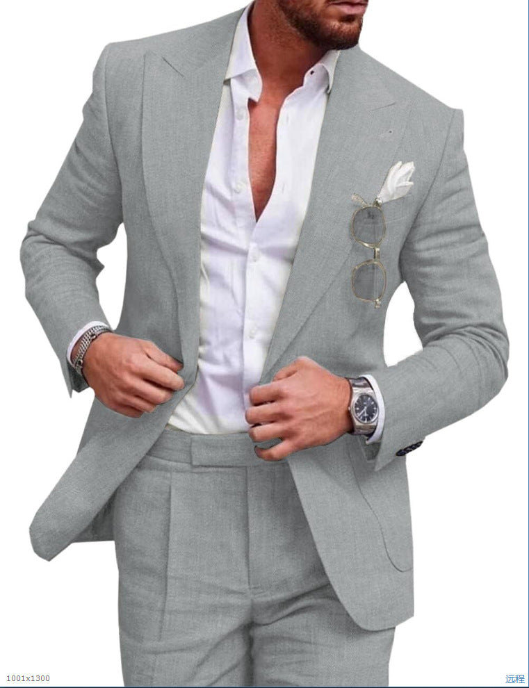 Homme en costume gris élégant, chemise blanche ouverte, lunettes de soleil accrochées, montre-bracelet argentée, mouchoir blanc dans la poche.