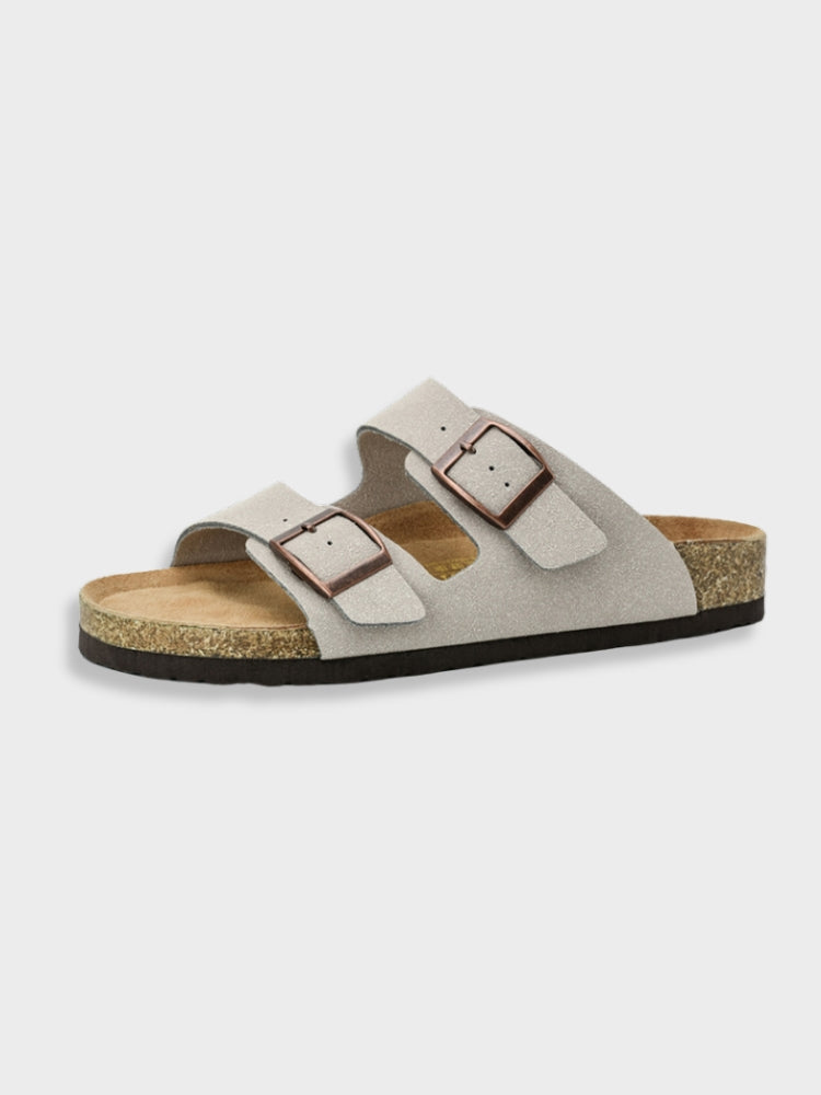 Sandale en cuir suédé gris avec semelle en liège, deux brides ajustables à boucles métalliques, style décontracté, confort optimal pour l'été.