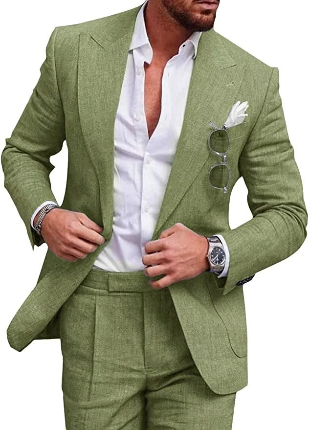Homme en costume vert élégant, chemise blanche ouverte, lunettes de soleil accrochées, montre-bracelet argentée, style mode masculine chic.