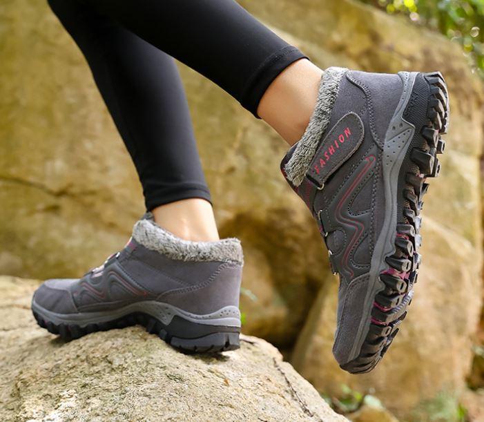 Chaussures de randonnée grises pour femme avec semelle antidérapante, portées sur un rocher. Idéales pour trekking et activités en plein air.