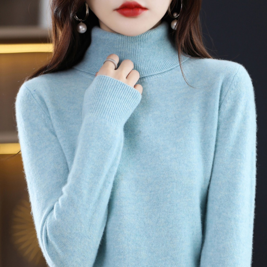 Femme portant un pull col roulé bleu clair, boucles d'oreilles pendantes, lèvres rouges. Mode hiver élégante, style moderne et chic.