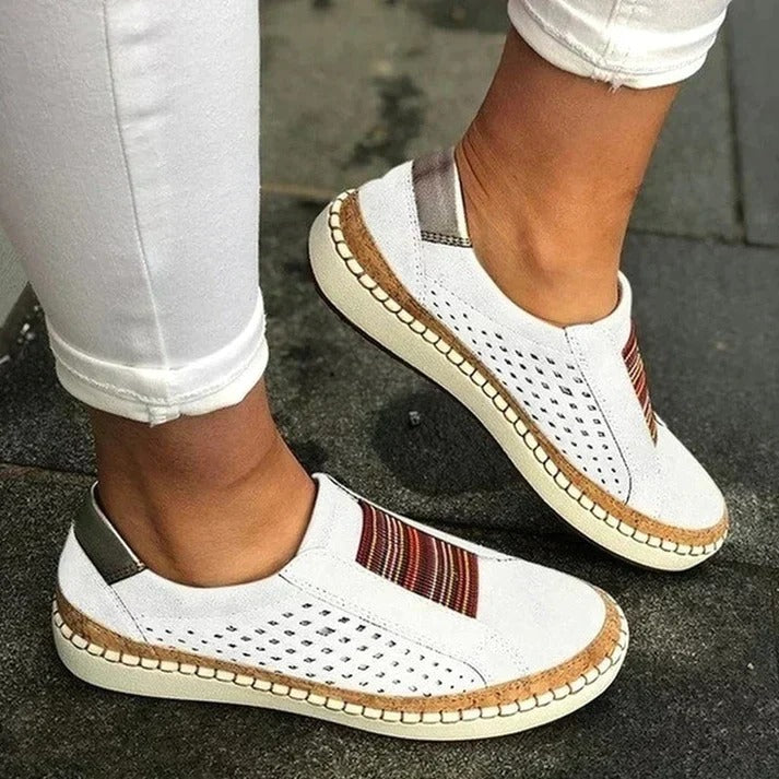 Chaussures blanches décontractées pour femmes avec motifs colorés, semelle en corde, portées avec un pantalon blanc. Mode estivale tendance.
