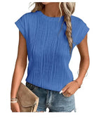 Femme portant un haut bleu plissé, manches courtes, avec un sac beige et un jean décontracté. Mode féminine, tenue estivale élégante.