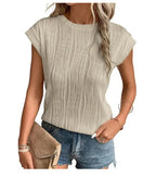 Femme portant un haut beige texturé à manches courtes, associé à un short en jean bleu et un sac à main beige. Mode estivale décontractée.