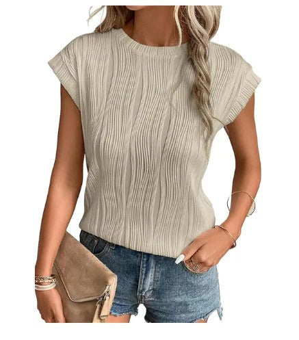 Femme portant un haut beige texturé à manches courtes, associé à un short en jean bleu et un sac à main beige. Mode estivale décontractée.