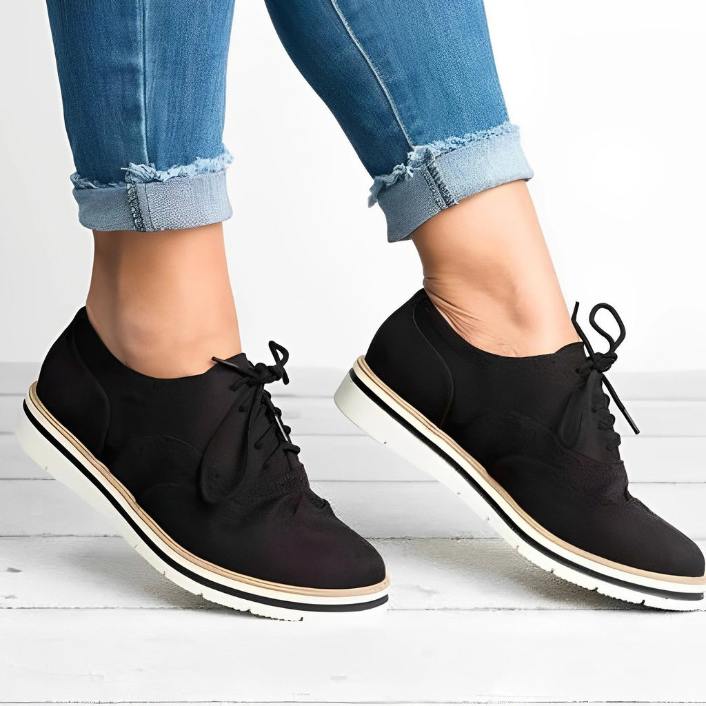 Chaussures noires élégantes pour femmes, style derby, portées avec un jean retroussé. Mode féminine, chaussures confortables, tendance automne.