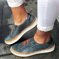 Chaussures décontractées en cuir bleu pour femme, avec semelle blanche et détails colorés, portées avec un pantalon blanc. Mode, confort, style urbain.