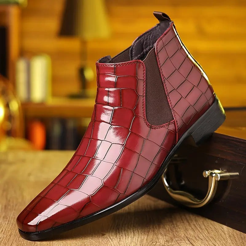 Bottine en cuir verni rouge à motif crocodile, style Chelsea, posée sur une table en bois, fond flou. Chaussure élégante pour homme.