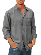 Homme portant une chemise en jean gris décontractée, manches longues, avec poche poitrine, style moderne. Mode masculine, tenue casual élégante.