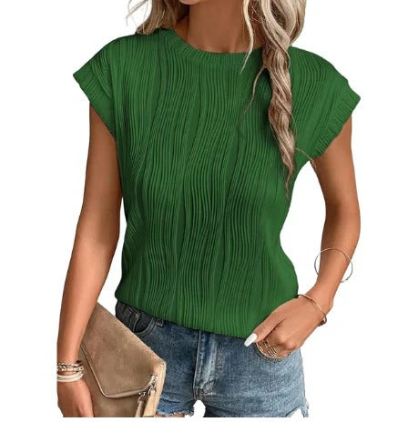 Femme portant un haut vert plissé, manches courtes, avec un sac beige et un jean. Mode féminine, tenue décontractée, style estival.