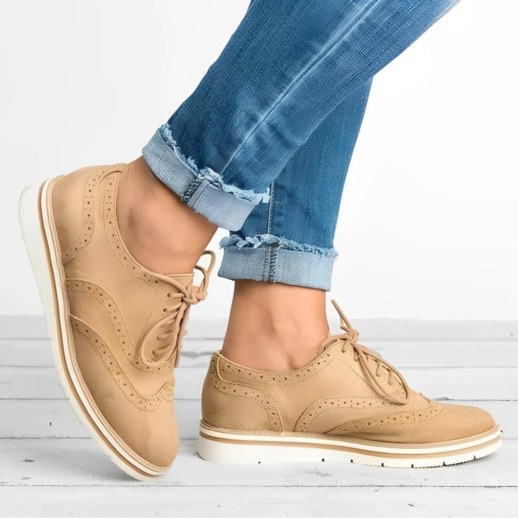 Chaussures derby beiges en cuir pour femme, portées avec un jean bleu décontracté. Style élégant et moderne, parfait pour la mode urbaine.