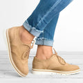 Chaussures derby beiges en cuir pour femme, portées avec un jean bleu décontracté. Style élégant et moderne, parfait pour la mode urbaine.