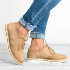 Chaussures derby beiges en cuir pour femme, portées avec un jean bleu décontracté. Style élégant et moderne, parfait pour la mode urbaine.