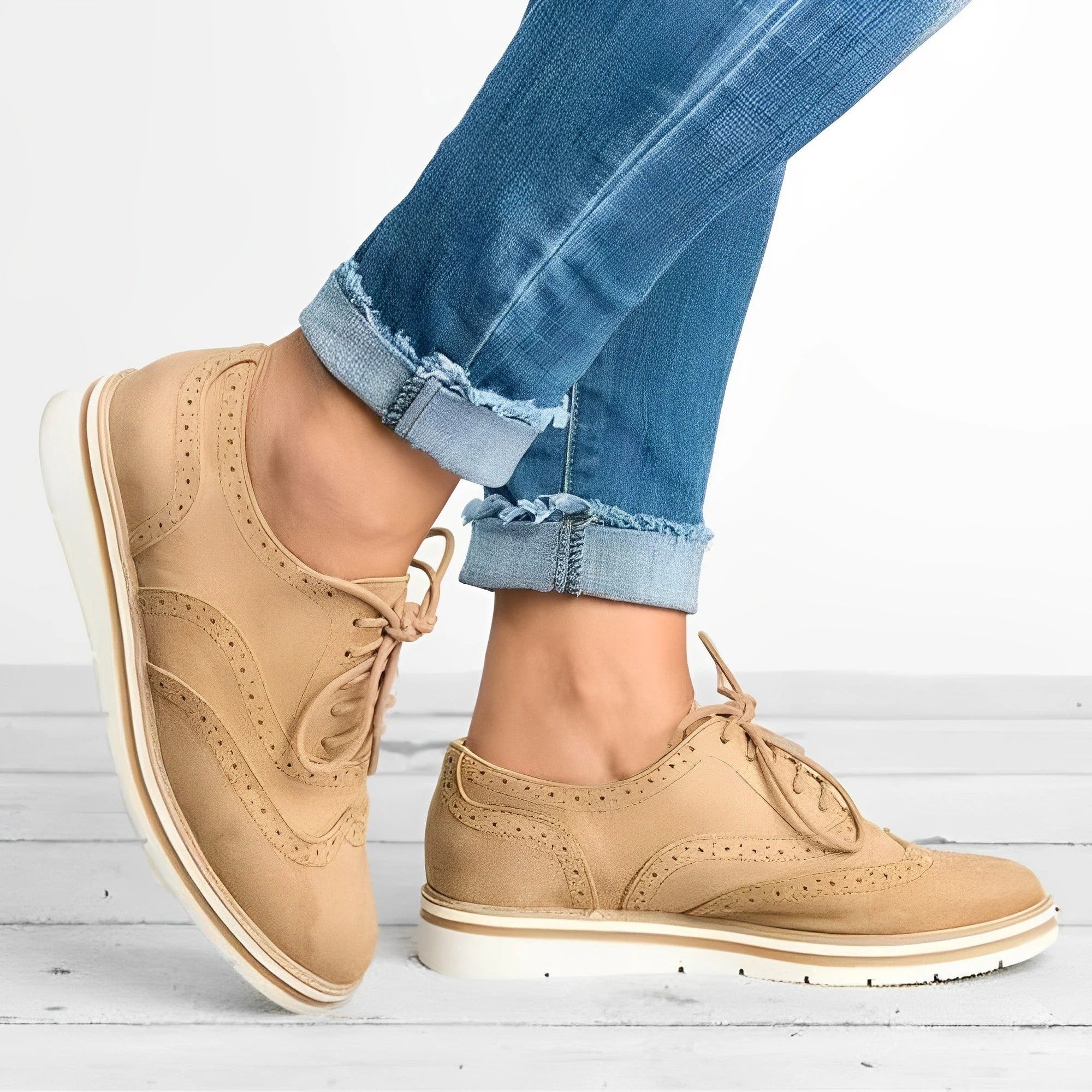 Chaussures derby beiges en cuir pour femme, portées avec un jean bleu décontracté. Style élégant et moderne, parfait pour la mode urbaine.