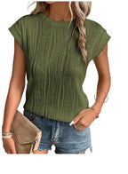 Femme portant un haut plissé vert olive et un short en jean, tenant une pochette beige. Mode estivale, tenue décontractée chic.