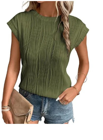 Femme portant un haut plissé vert olive et un short en jean, tenant une pochette beige. Mode estivale, tenue décontractée chic.