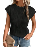 Femme portant un haut noir plissé, manches courtes, avec un short en jean. Accessoires: sac beige, bracelet doré. Mode décontractée chic.