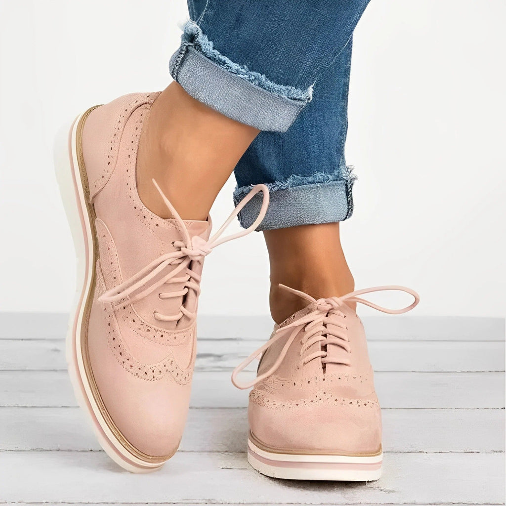 Chaussures derby rose pastel pour femme, en cuir suédé, avec lacets, portées avec un jean bleu décontracté. Mode féminine élégante et tendance.