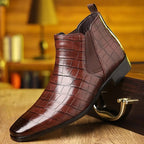 Chaussure en cuir marron à motif croco, style chelsea, posée sur une surface en bois, fond flou. Mode homme élégante, tendance automne.