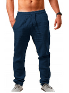 Homme portant un pantalon de jogging bleu marine, taille élastique, poches latérales, chaussures grises, torse nu, montre noire.